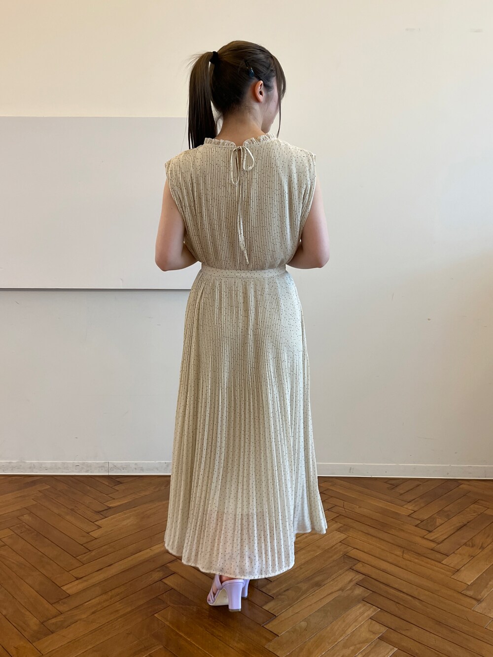 ベージュ系のワンピース、ベージュ系のハンドバッグ、パープル系のサンダルを着用したレディースの春コーディネートの3枚目の写真