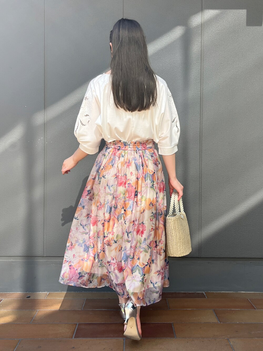 ホワイト系のTシャツ/カットソー、オレンジ系のスカートを着用したレディースの春コーディネートの2枚目の写真