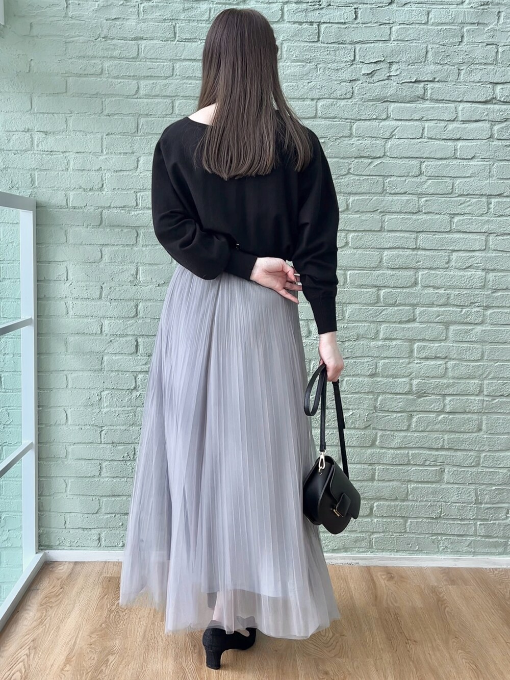 グレー系のスカート、ブラック系のニット/セーターを着用したレディースの秋コーディネートの3枚目の写真