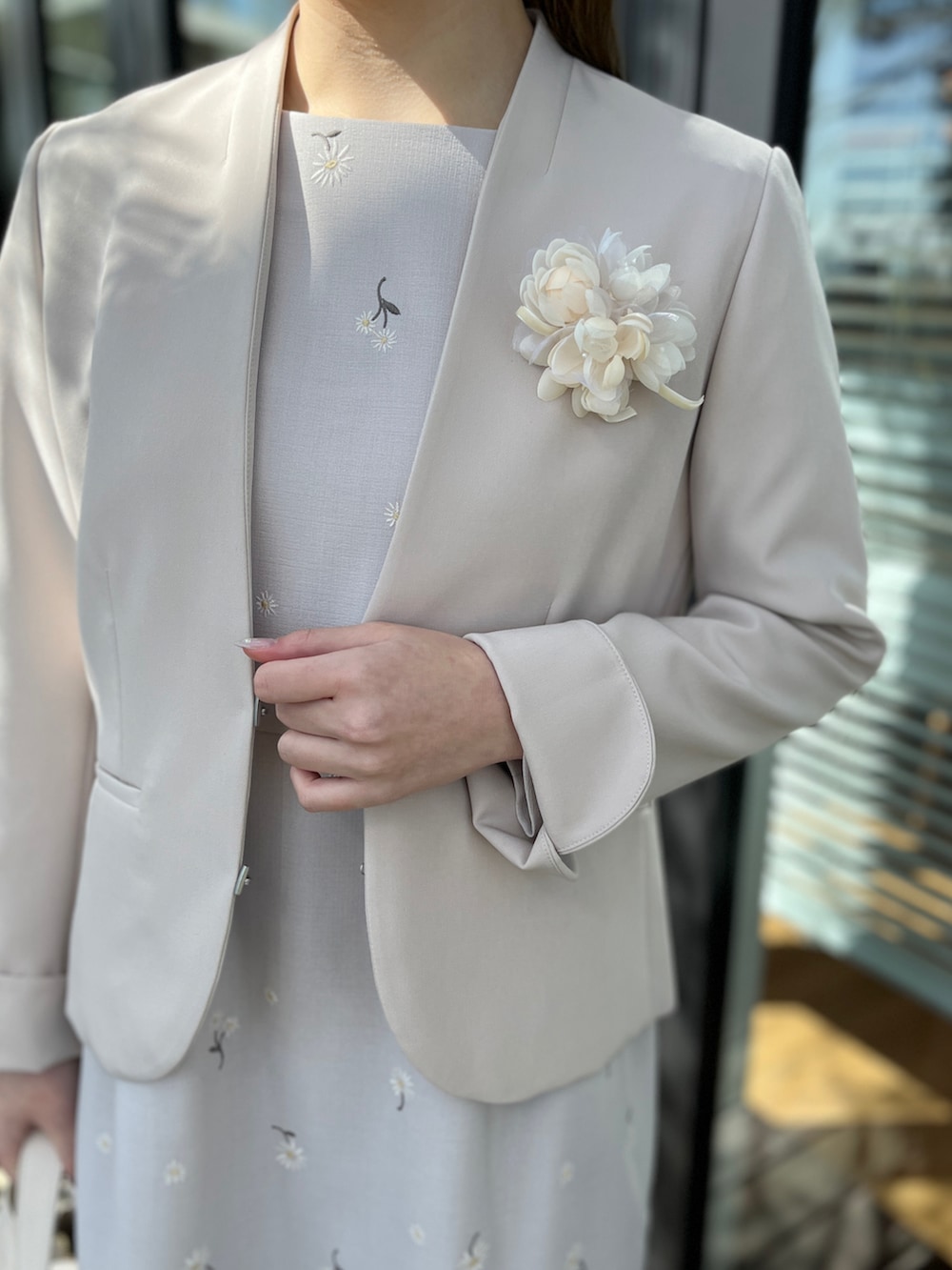 グレー系のワンピース、グレー系のノーカラージャケット、ベージュ系のパンプスを着用したレディースの春コーディネートの4枚目の写真