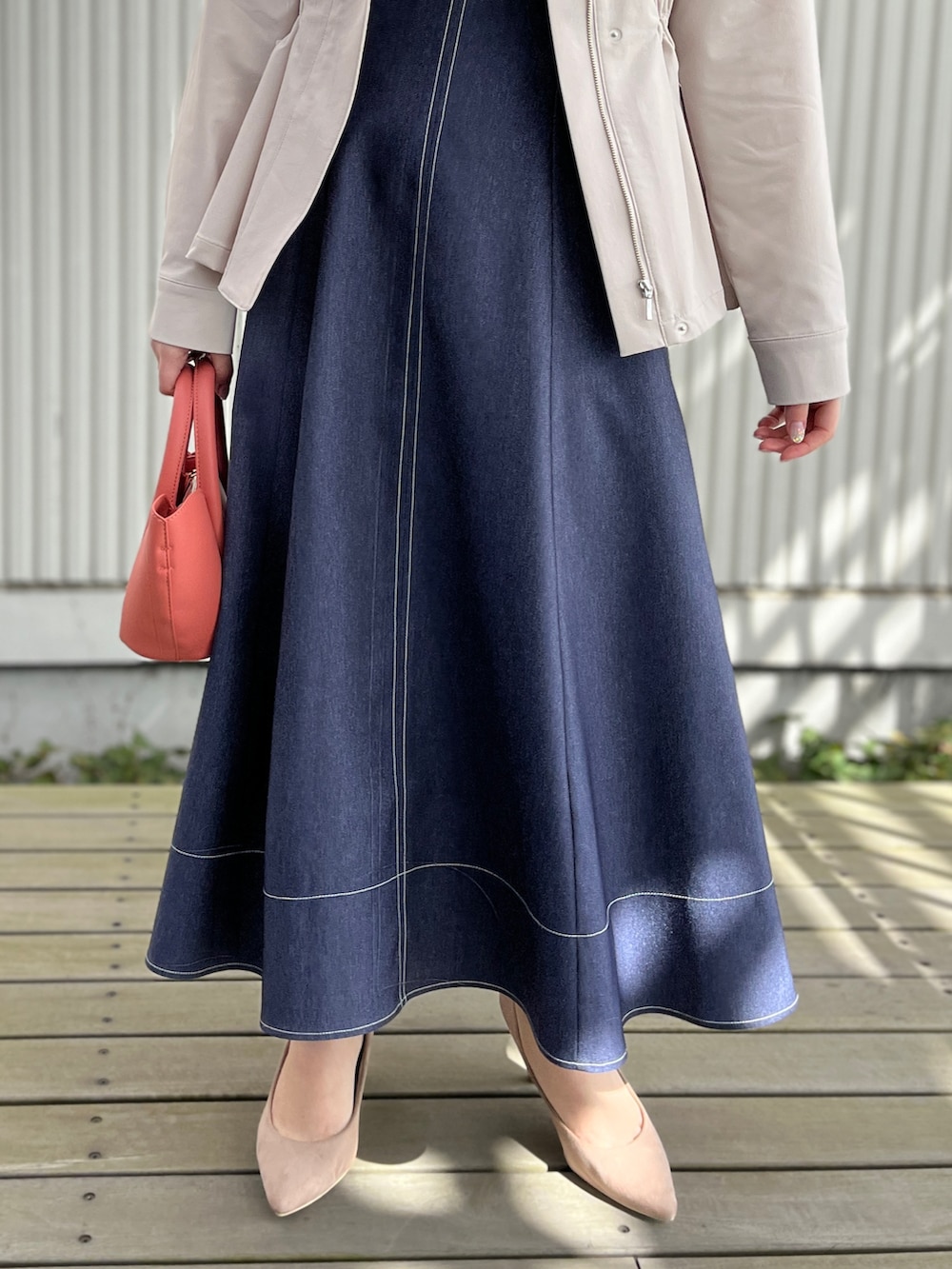 グレー系のブルゾン、ホワイト系のTシャツ/カットソー、ブルー系のスカートを着用したレディースの春コーディネートの5枚目の写真