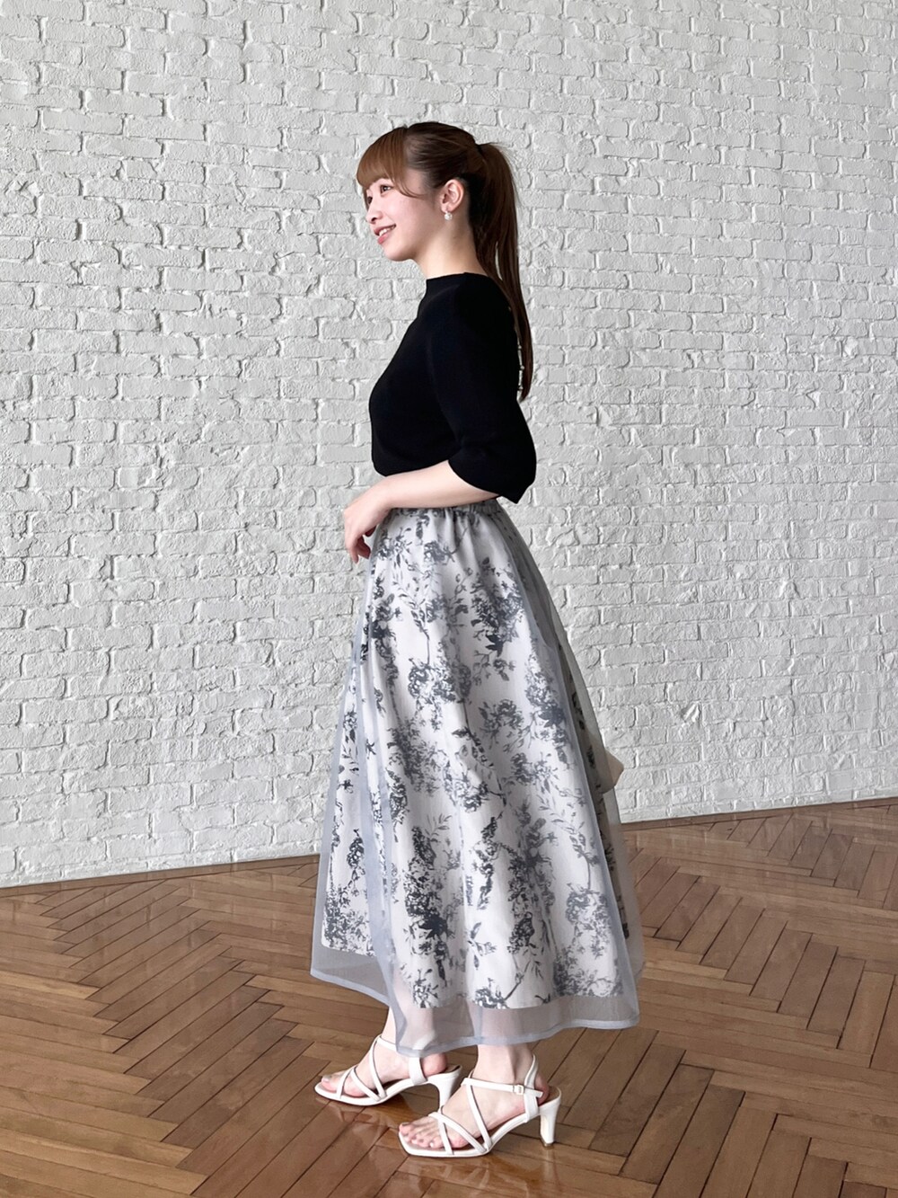 ブラック系のニット/セーター、グレー系のスカート、ホワイト系のショルダーバッグを着用したレディースの夏コーディネートの2枚目の写真