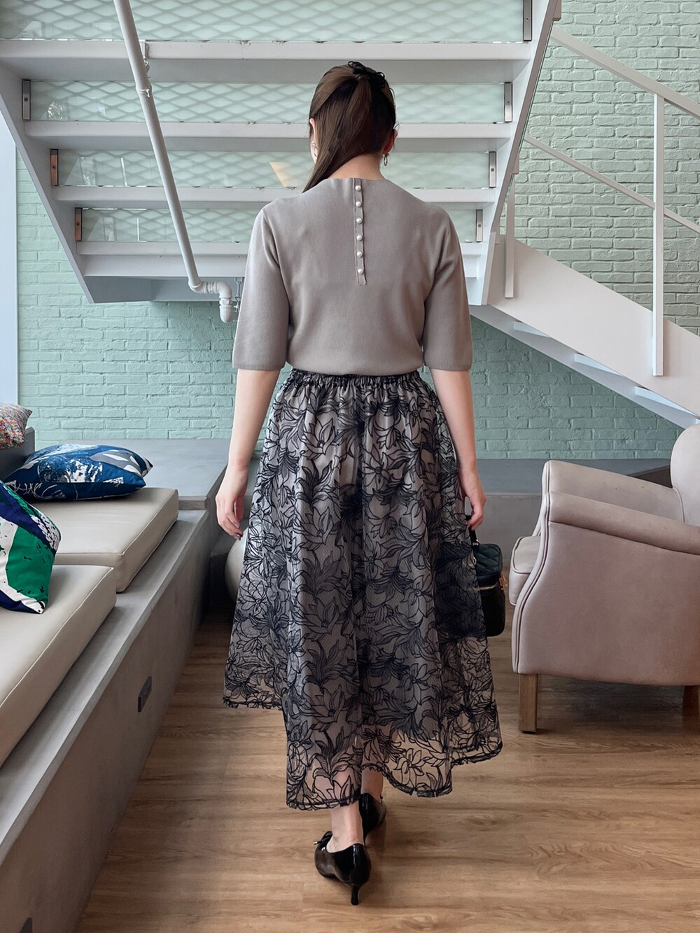 グリーン系のニット/セーター、ブラック系のショルダーバッグ、ブラック系のスカートを着用したレディースの夏コーディネートの3枚目の写真