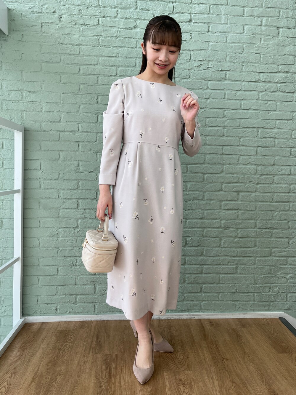 グレー系のワンピース、ベージュ系のパンプス、ホワイト系のショルダーバッグを着用したレディースの冬コーディネートの3枚目の写真