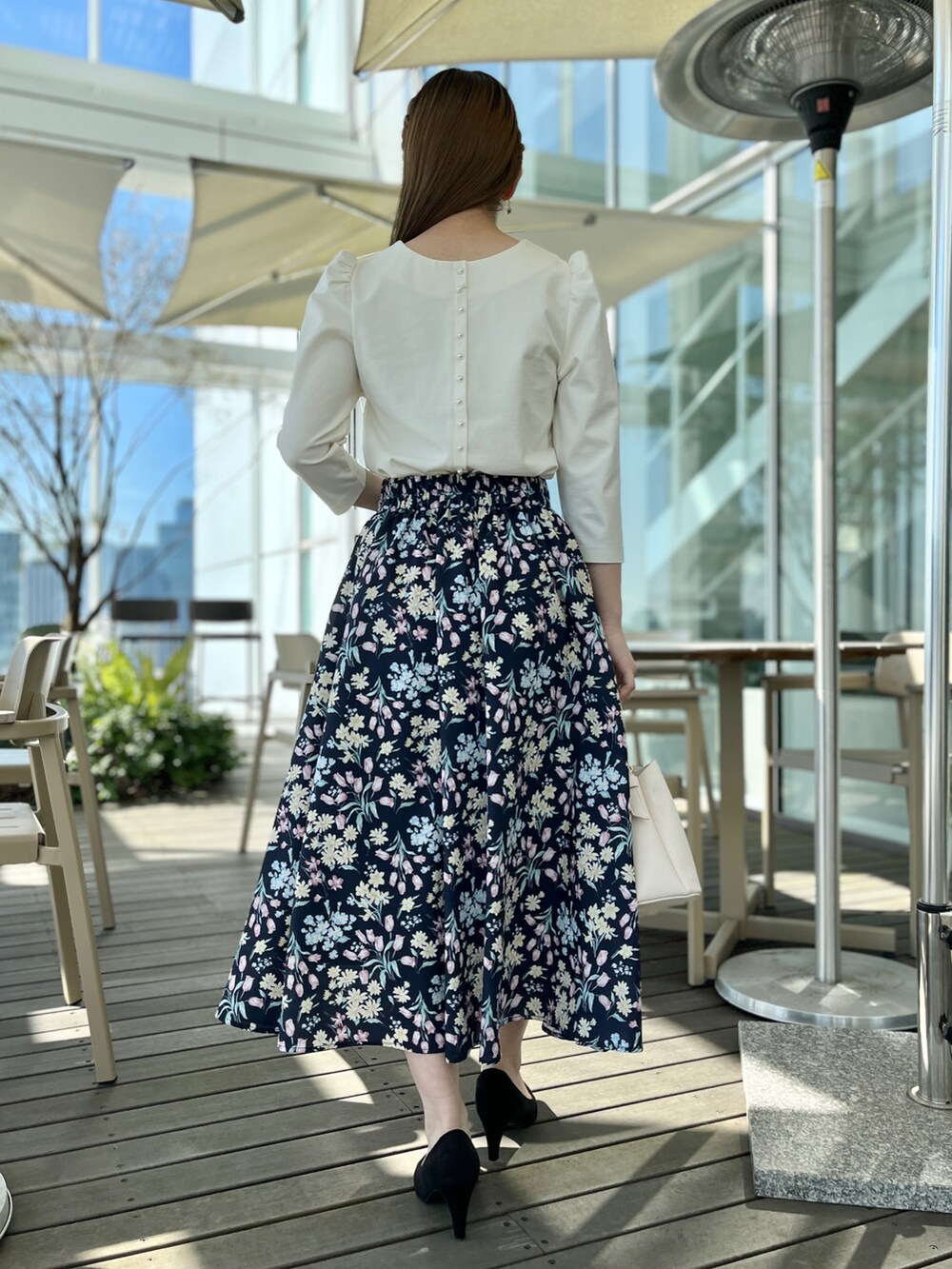 ホワイト系のTシャツ/カットソー、ブルー系のスカート、ブラック系のパンプスを着用したレディースの春コーディネートの3枚目の写真