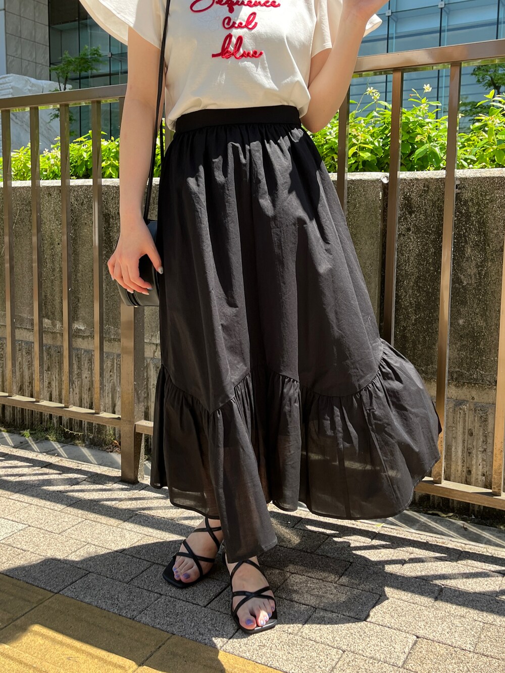 ホワイト系のTシャツ/カットソー、ブラック系のショルダーバッグ、ブラック系のスカートを着用したレディースの春コーディネートの5枚目の写真