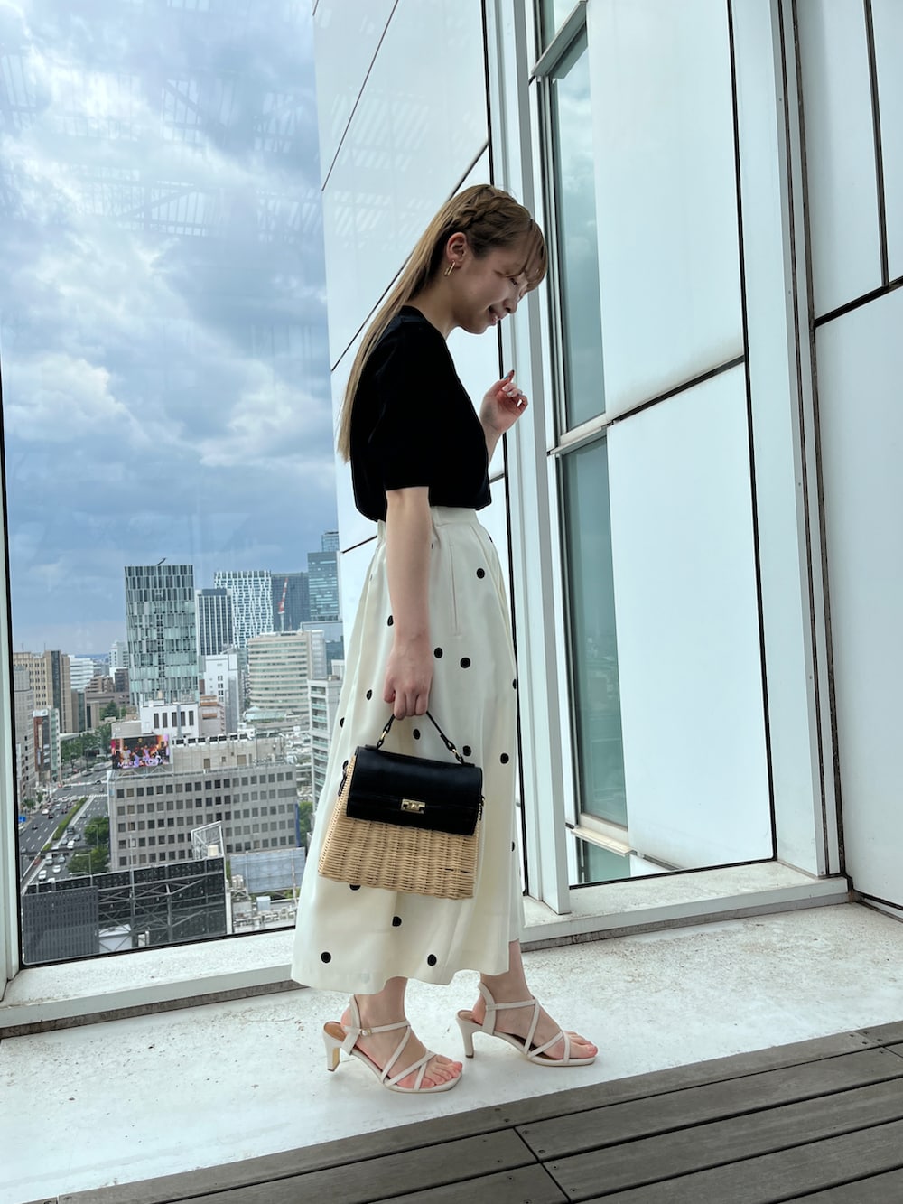 ブラック系のニット/セーター、ベージュ系のスカート、ブラック系のショルダーバッグを着用したレディースの春コーディネートの2枚目の写真