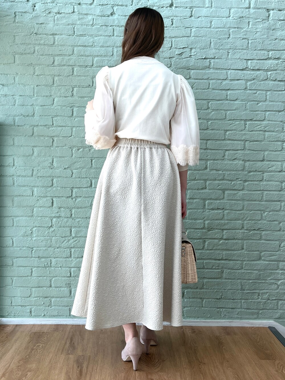 ベージュ系のスカート、ホワイト系のニット/セーター、グレー系のショルダーバッグを着用したレディースの春コーディネートの3枚目の写真