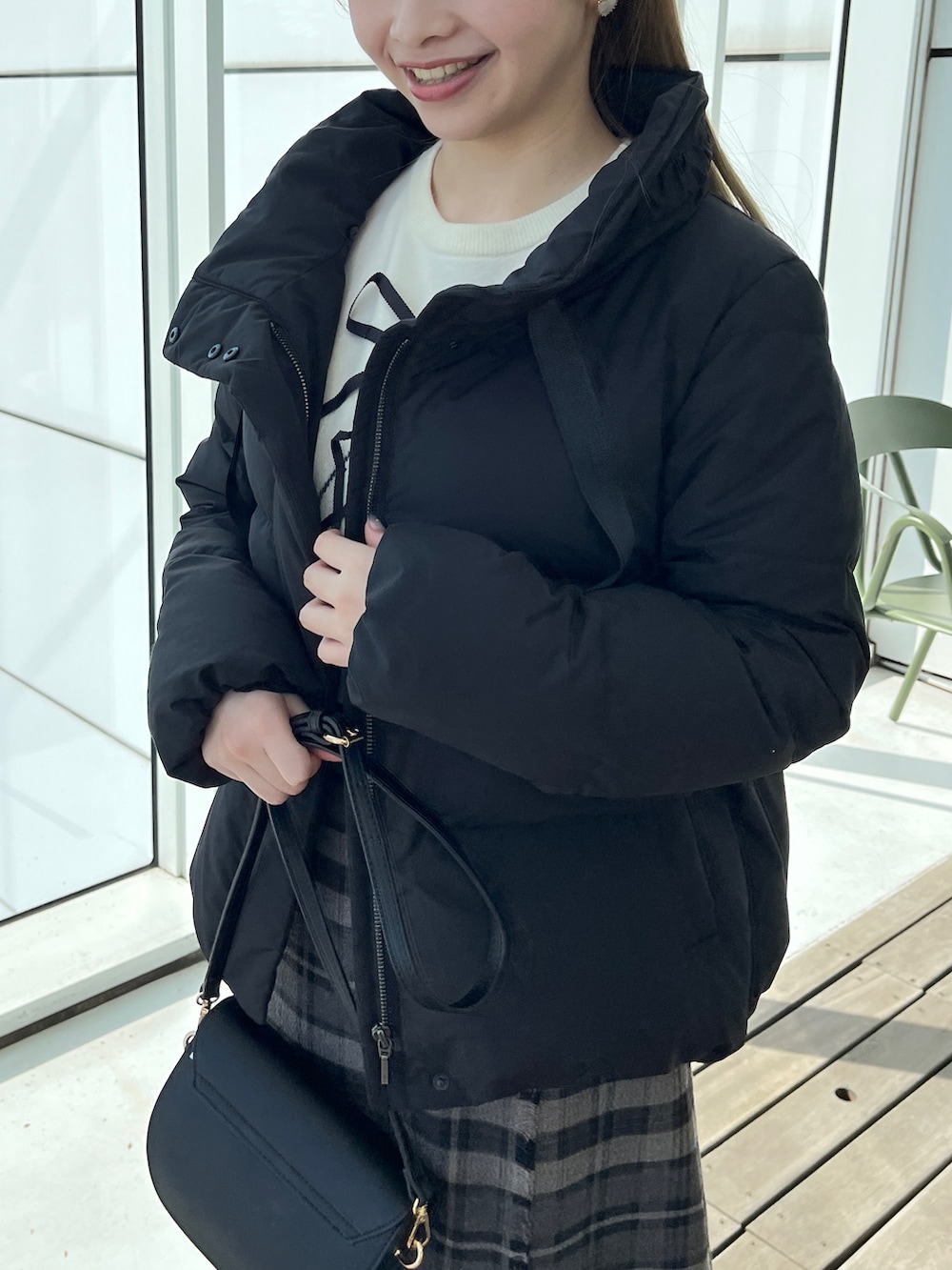 ブラック系のダウンジャケット/コート、ホワイト系のニット/セーター、グレー系のスカートを着用したレディースの秋コーディネートの3枚目の写真