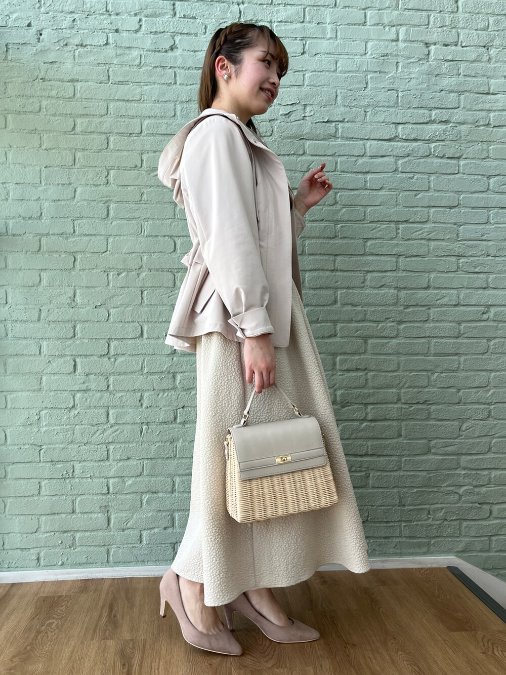 ベージュ系のスカート、ホワイト系のニット/セーター、グレー系のブルゾンを着用したレディースの春コーディネートの2枚目の写真