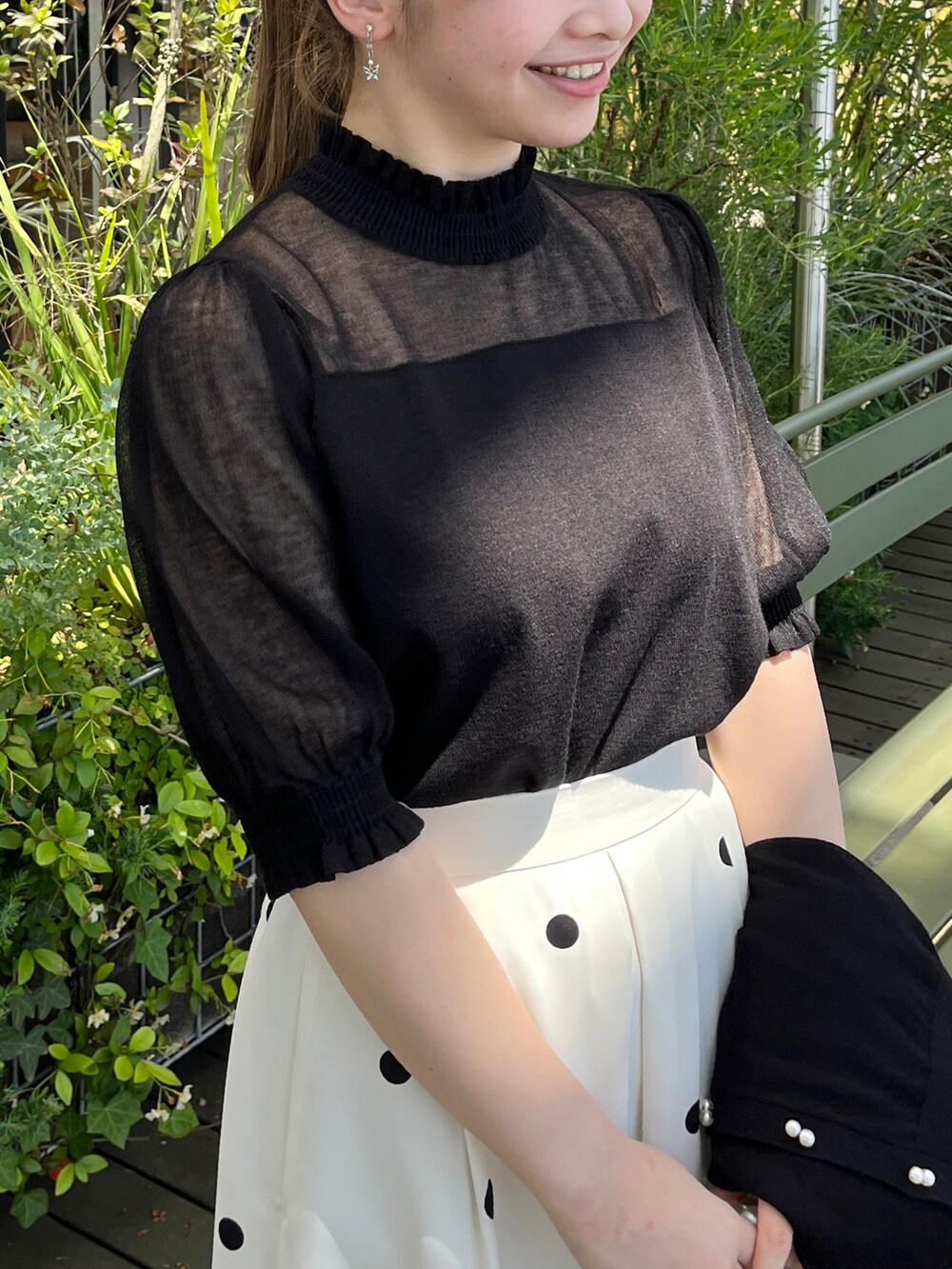 ブラック系のニット/セーター、ブラック系のカーディガン/ボレロ、ベージュ系のスカートを着用したレディースの夏コーディネートの4枚目の写真