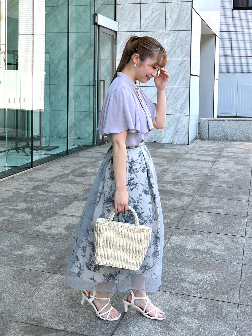 グレー系のシャツ/ブラウス、ベージュ系のハンドバッグ、ホワイト系のサンダルを着用したレディースの夏コーディネートの2枚目の写真