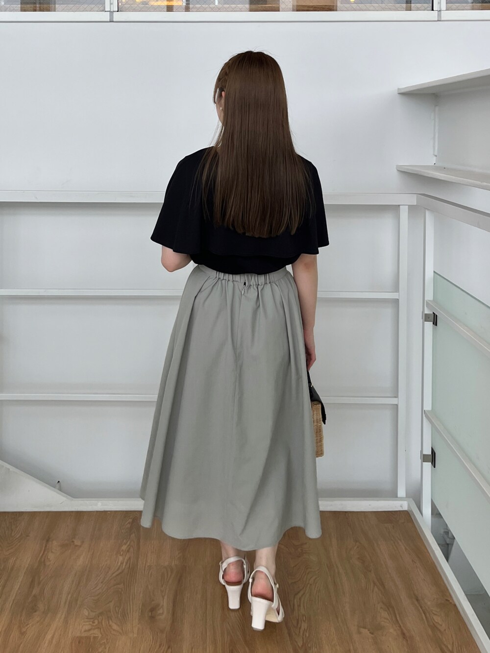 ブラック系のショルダーバッグ、ホワイト系のサンダル、ブラック系のTシャツ/カットソーを着用したレディースの夏コーディネートの3枚目の写真