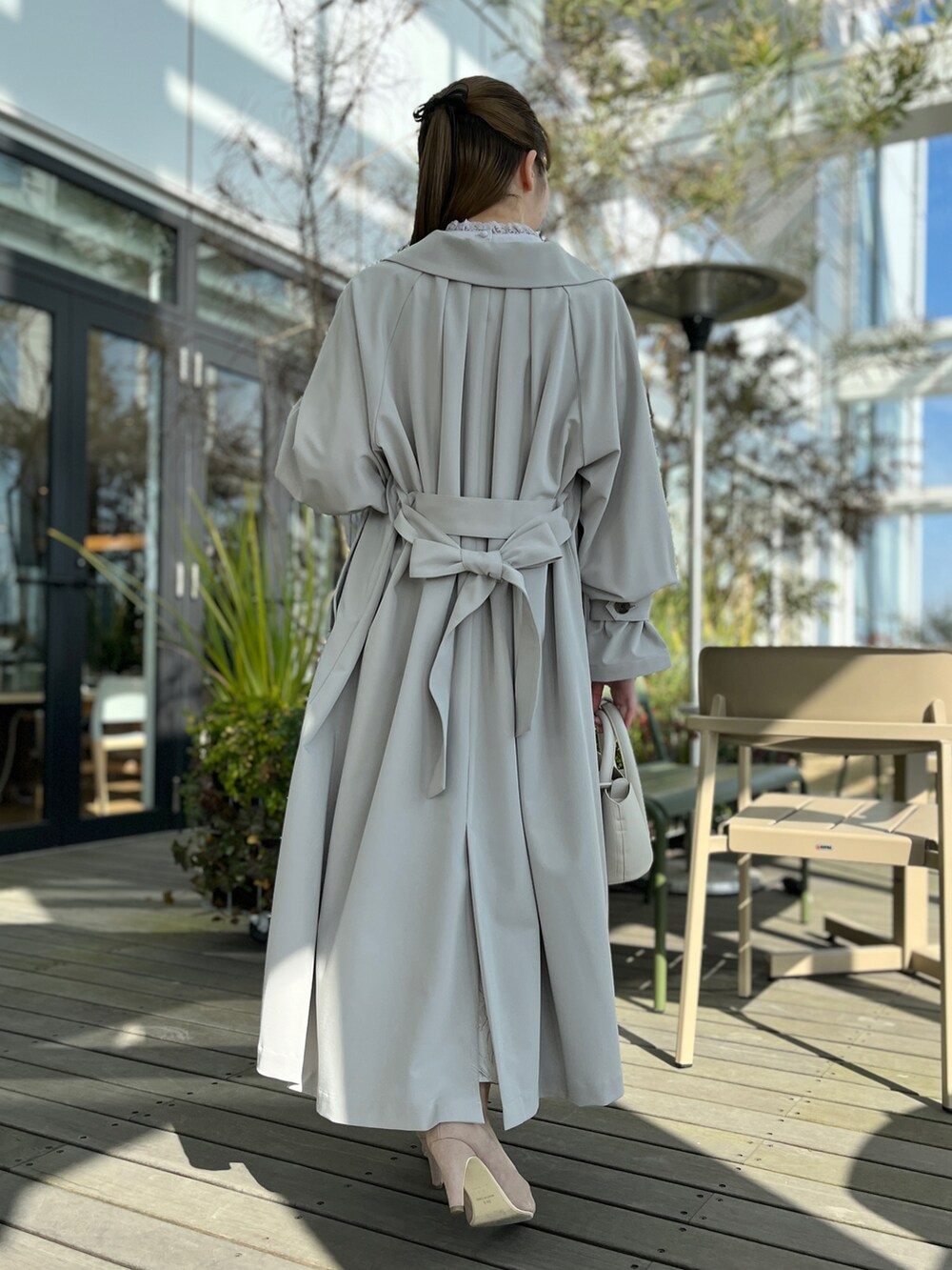 グレー系のトレンチコート、グレー系のシャツ/ブラウス、ベージュ系のスカートを着用したレディースの冬コーディネートの3枚目の写真
