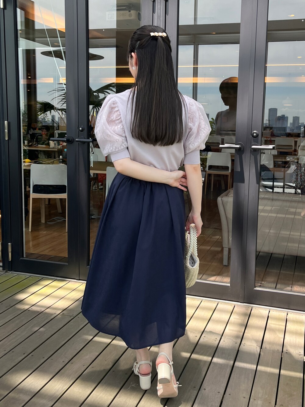 グレー系のニット/セーター、ブルー系のスカートを着用したレディースの春コーディネートの2枚目の写真