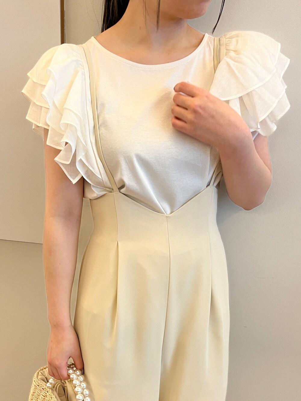 ベージュ系のハンドバッグ、ホワイト系のサンダル、ホワイト系のTシャツ/カットソーを着用したレディースの春コーディネートの4枚目の写真