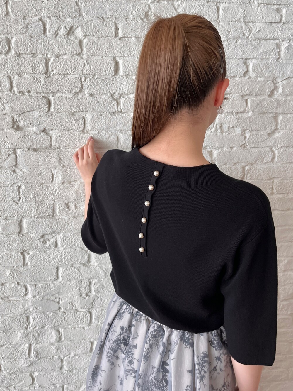 ブラック系のニット/セーター、グレー系のスカート、ホワイト系のショルダーバッグを着用したレディースの夏コーディネートの4枚目の写真