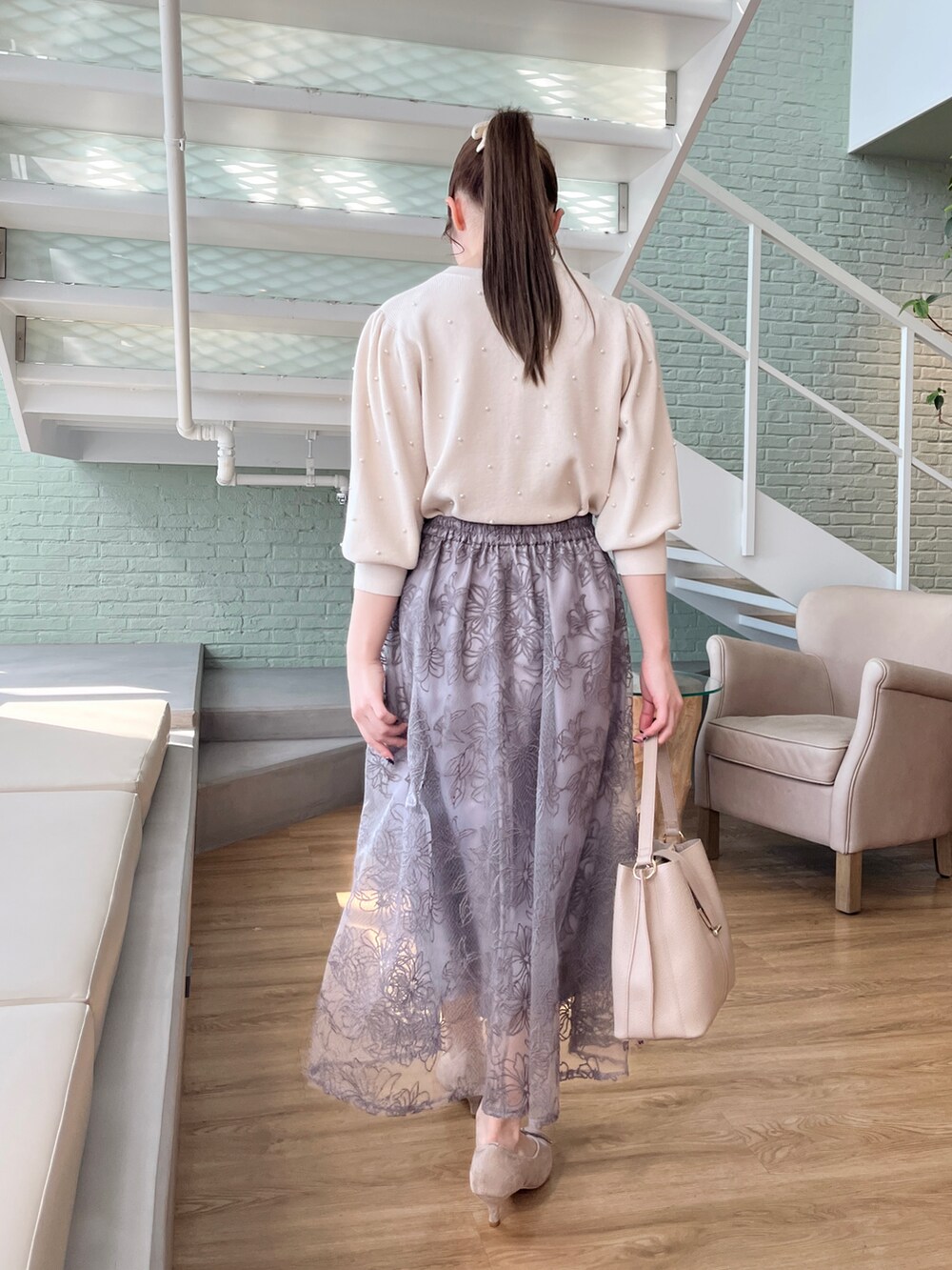 ホワイト系のニット/セーター、ベージュ系のその他アウター、グレー系のスカートを着用したレディースの冬コーディネートの4枚目の写真