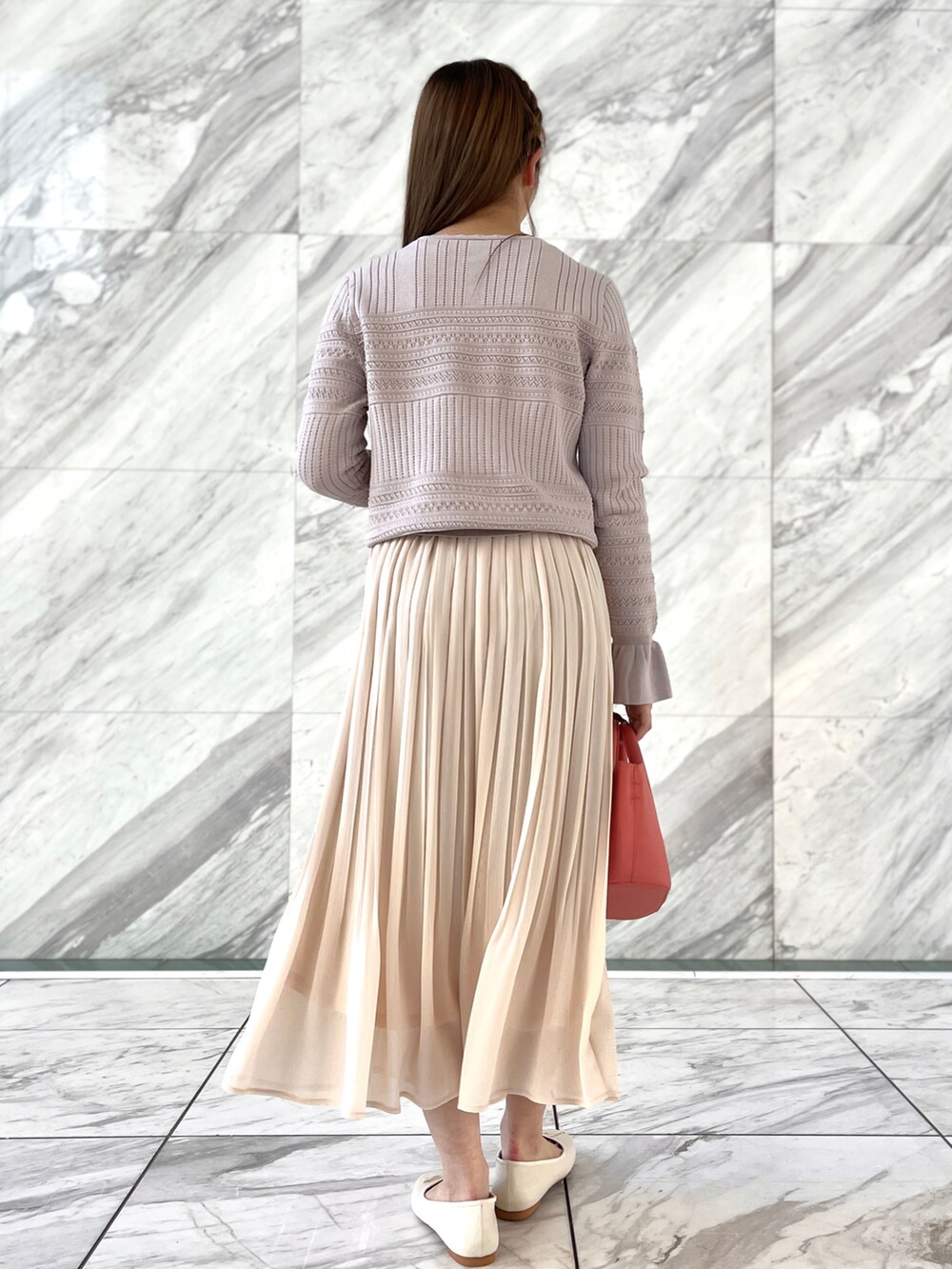 ピンク系のニット/セーター、ホワイト系のスカート、ホワイト系のパンプスを着用したレディースの冬コーディネートの3枚目の写真