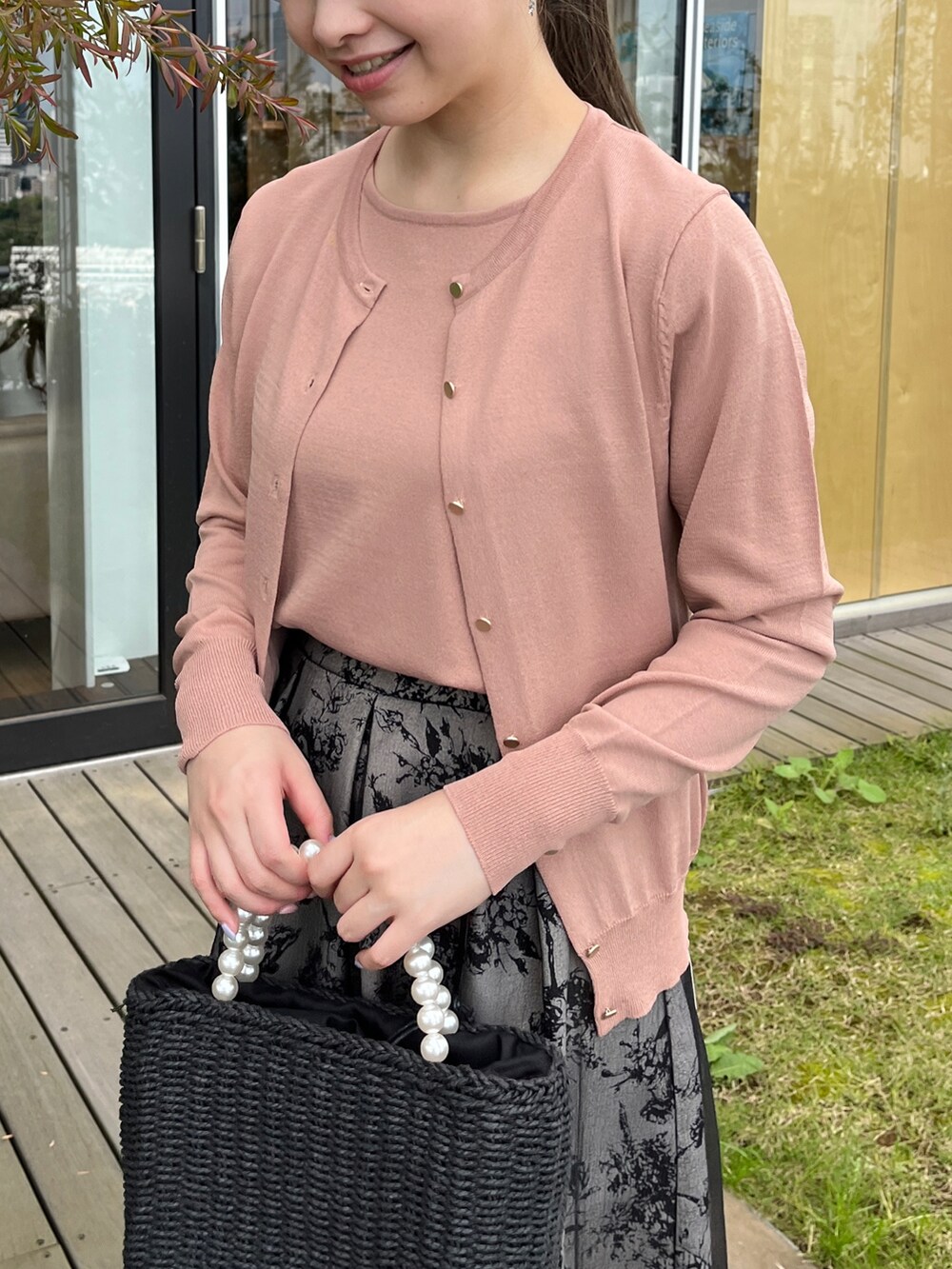 ブラック系のハンドバッグ、ブラック系のサンダル、ピンク系のニット/セーターを着用したレディースの夏コーディネートの3枚目の写真