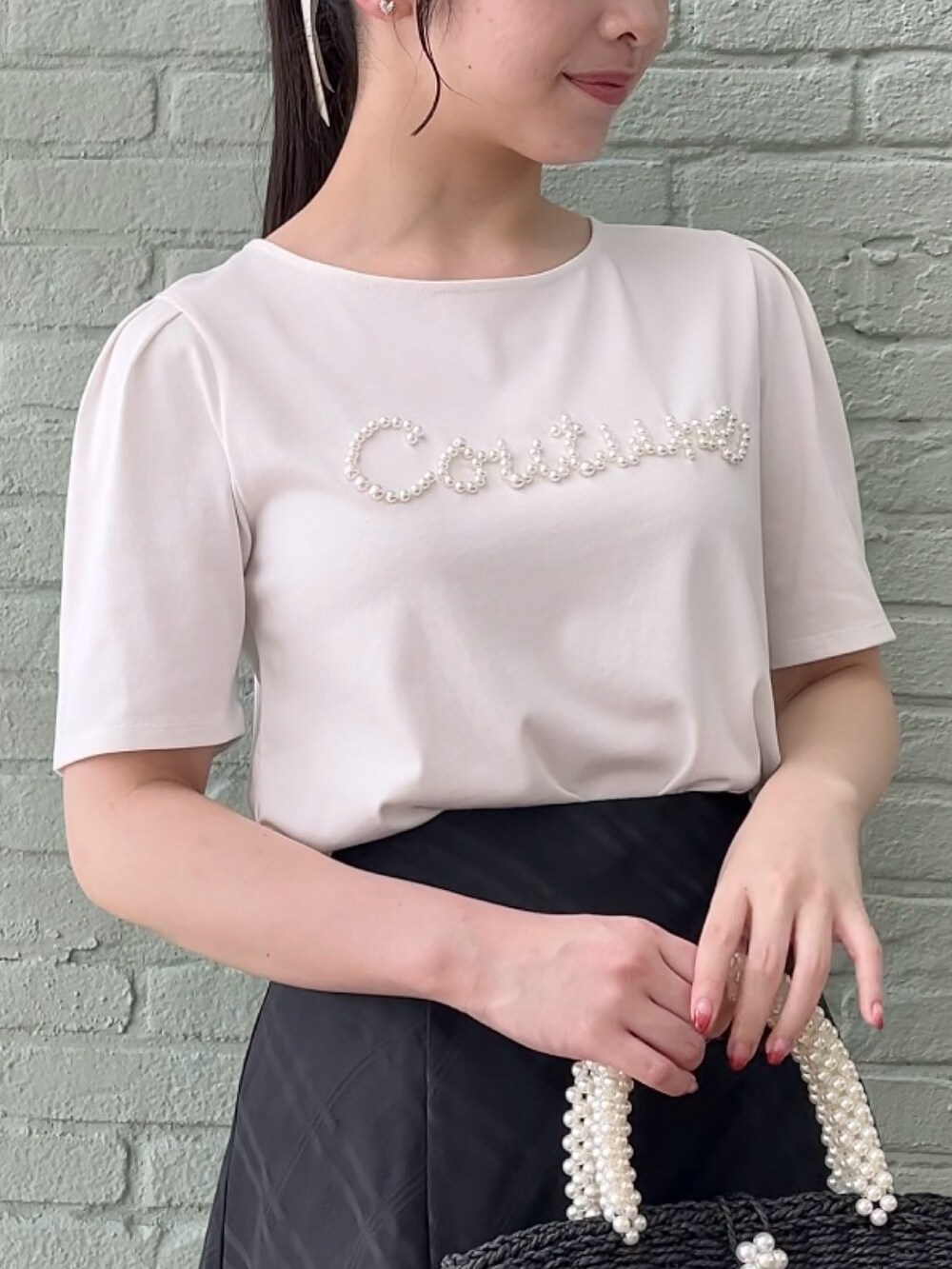 ブラック系のスカート、ホワイト系のTシャツ/カットソーを着用したレディースの夏コーディネートの4枚目の写真