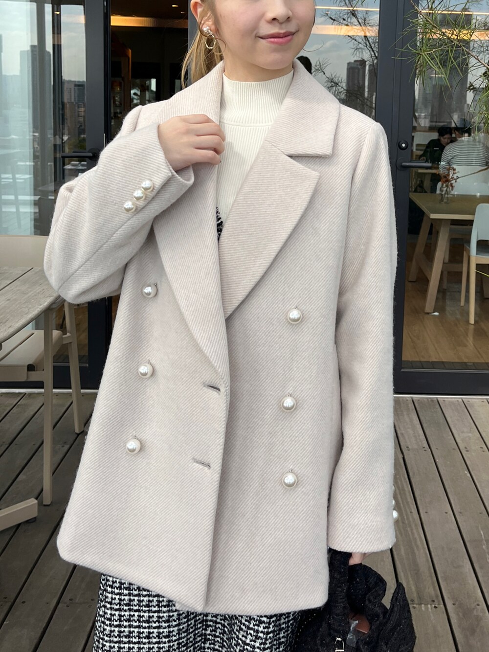 ベージュ系のピーコート、ブラック系のワンピースを着用したレディースの冬コーディネートの4枚目の写真