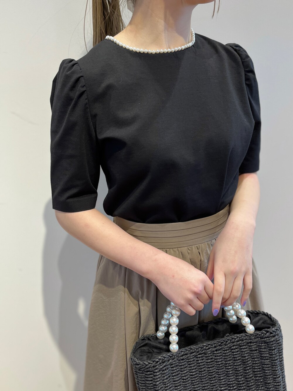 ブラック系のTシャツ/カットソー、ベージュ系のスカート、ブラック系のパンプスを着用したレディースの春コーディネートの4枚目の写真