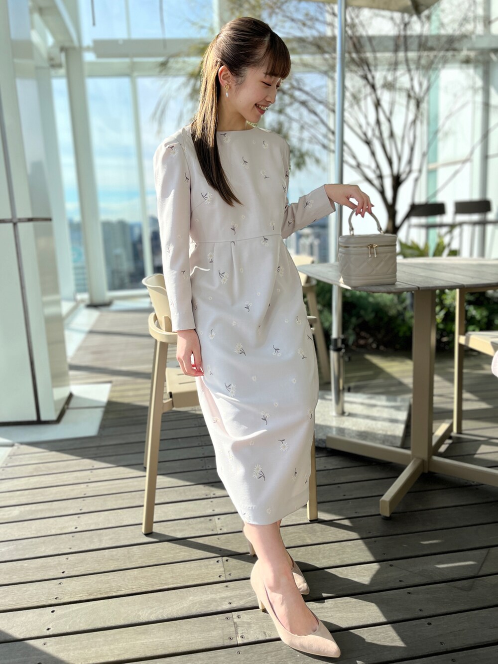 グレー系のワンピース、ベージュ系のパンプス、ホワイト系のショルダーバッグを着用したレディースの冬コーディネートの2枚目の写真