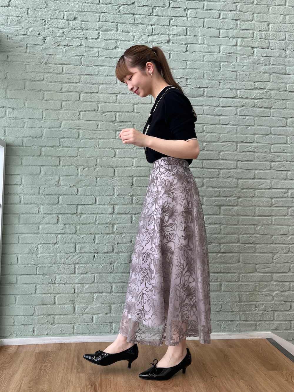 ブラック系のニット/セーター、グレー系のスカート、ブラック系のショルダーバッグを着用したレディースの夏コーディネートの2枚目の写真