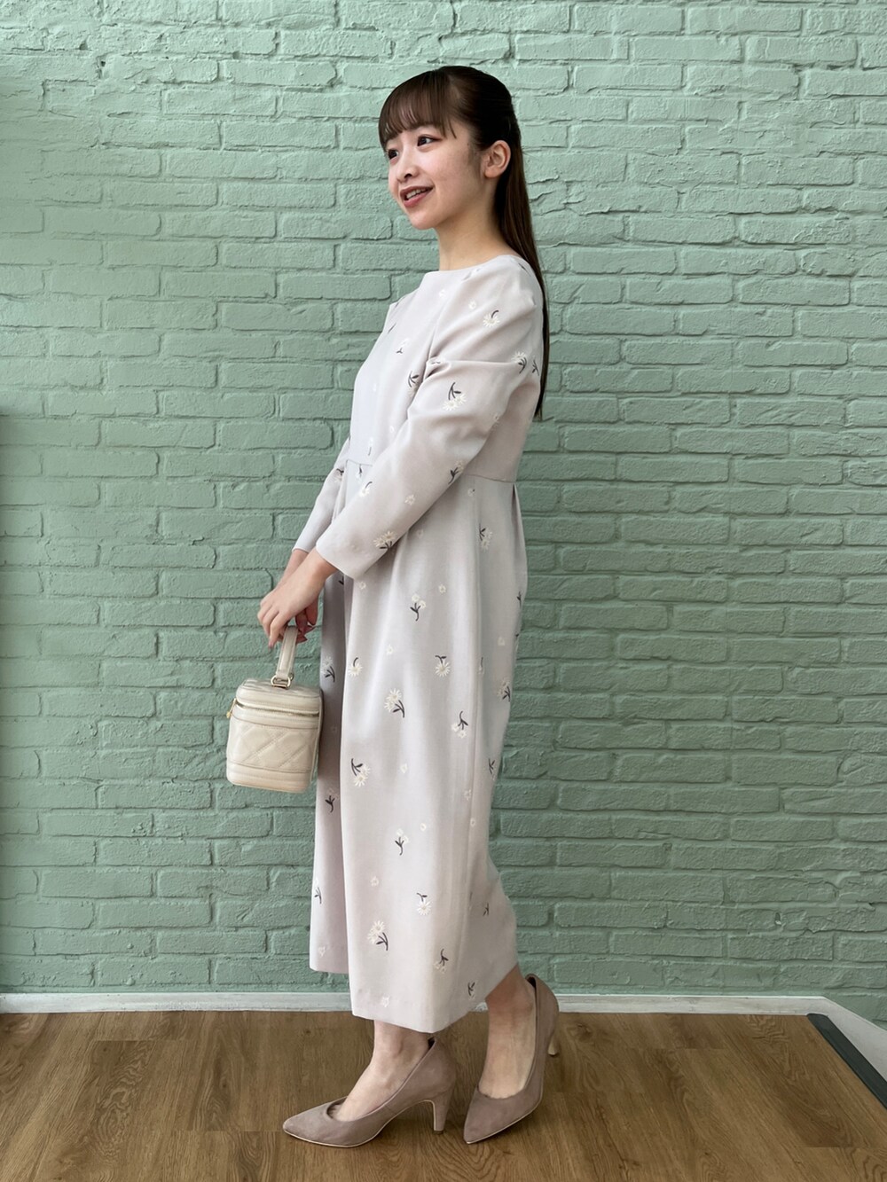 グレー系のワンピース、ベージュ系のパンプス、ホワイト系のショルダーバッグを着用したレディースの冬コーディネートの4枚目の写真