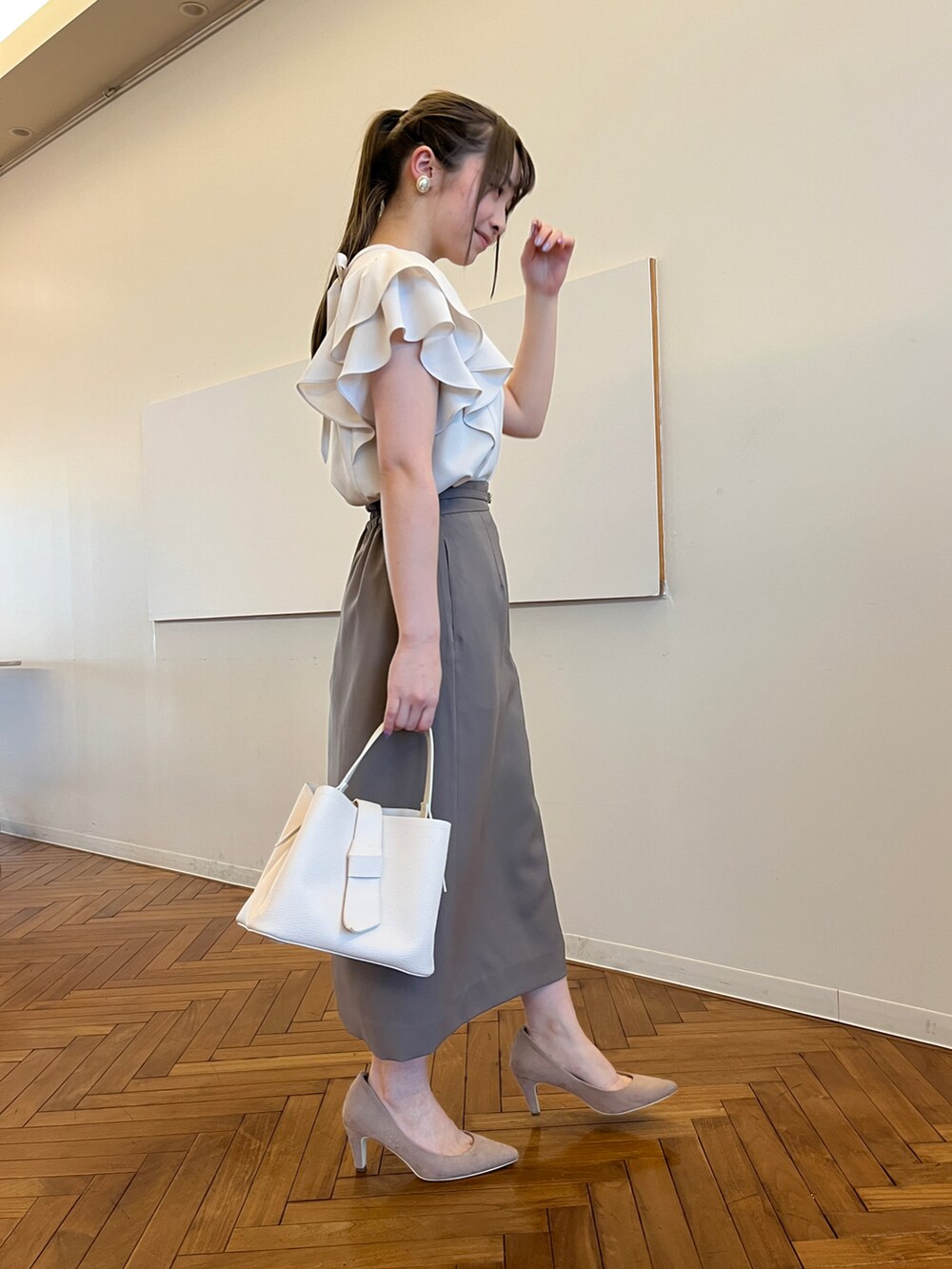 ブラウン系のスカート、ホワイト系のショルダーバッグ、ベージュ系のパンプスを着用したレディースの春コーディネートの2枚目の写真