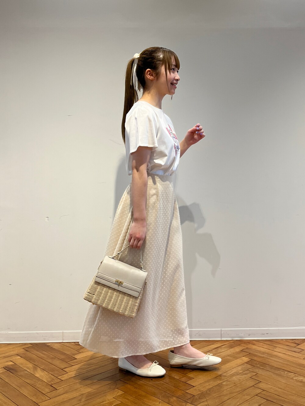 ホワイト系のTシャツ/カットソー、ホワイト系のスカート、グレー系のショルダーバッグを着用したレディースの春コーディネートの2枚目の写真