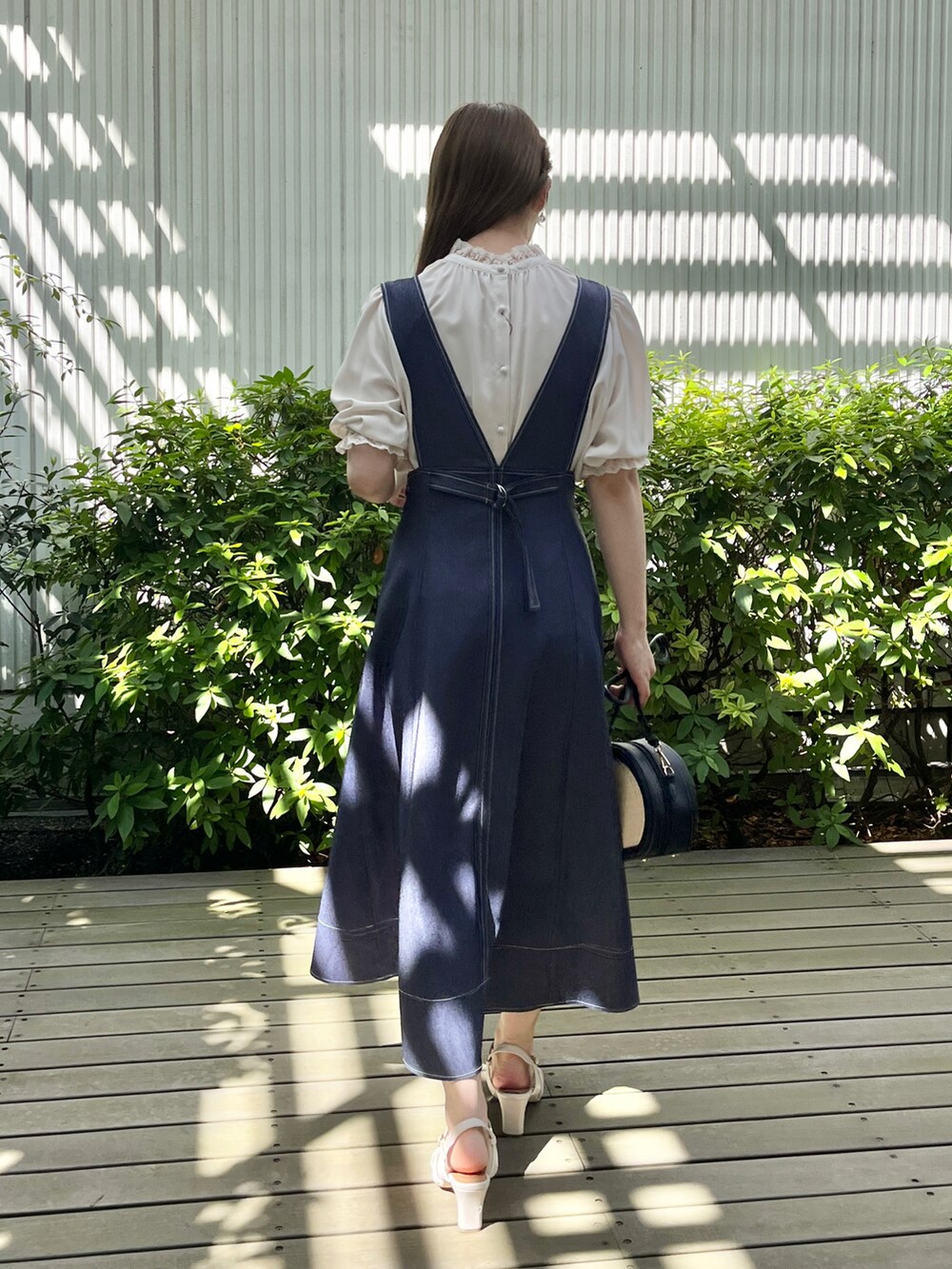 ブルー系のスカート、ホワイト系のサンダル、ブラック系のショルダーバッグを着用したレディースの夏コーディネートの3枚目の写真
