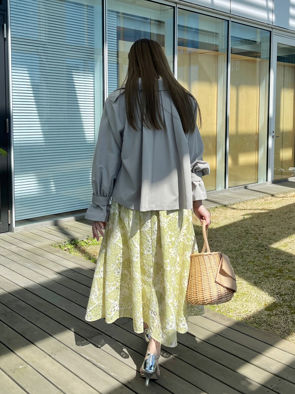 グレー系のトレンチコート、ホワイト系のワンピースを着用したレディースの春コーディネートの3枚目の写真