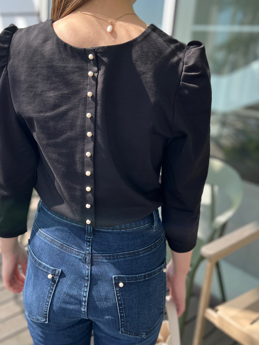 ブルー系のデニムパンツ、ブラック系のTシャツ/カットソー、ベージュ系のパンプスを着用したレディースの春コーディネートの4枚目の写真