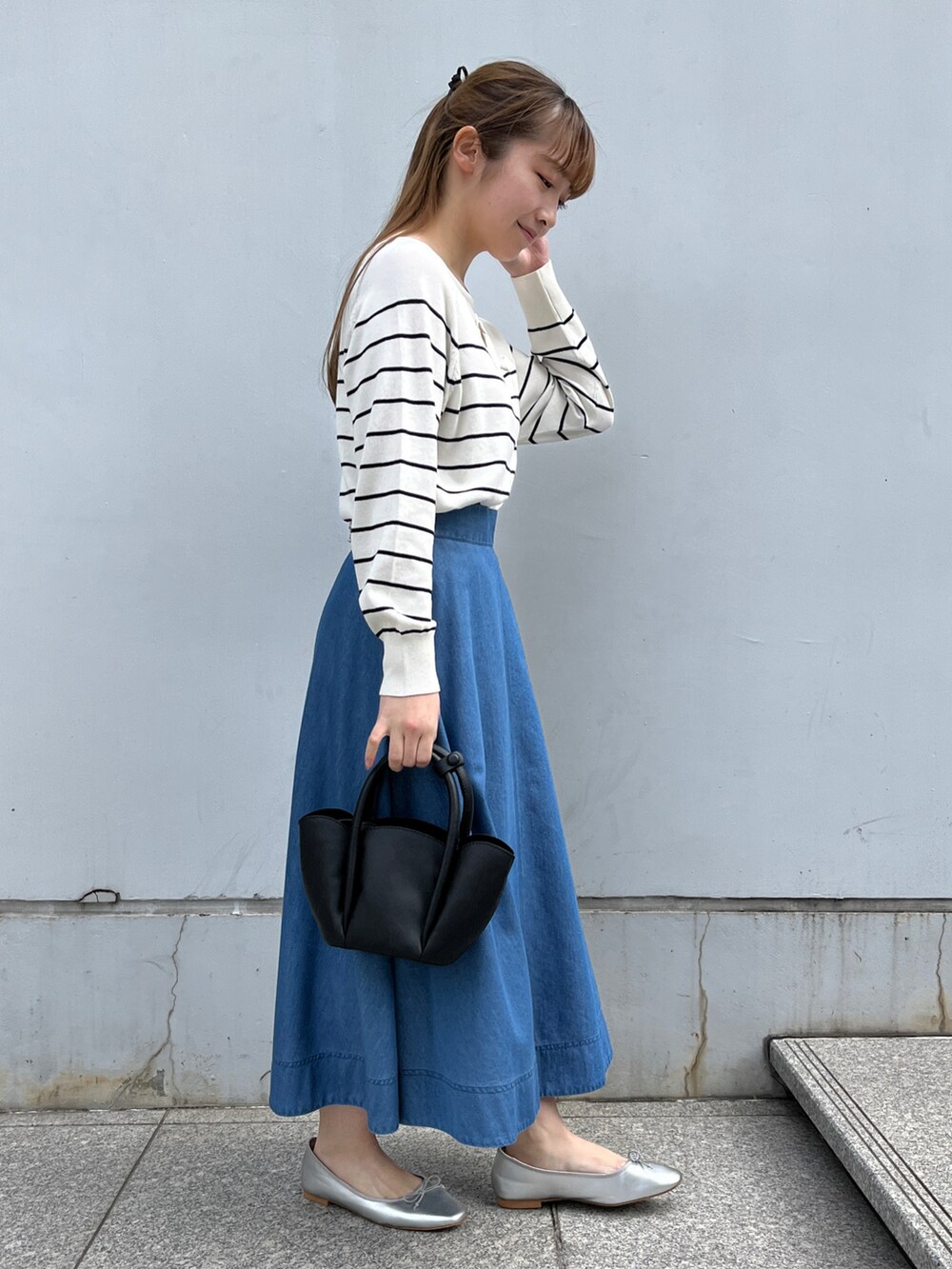 ホワイト系のニット/セーター、ブルー系のスカート、ブラック系のショルダーバッグを着用したレディースの冬コーディネートの2枚目の写真