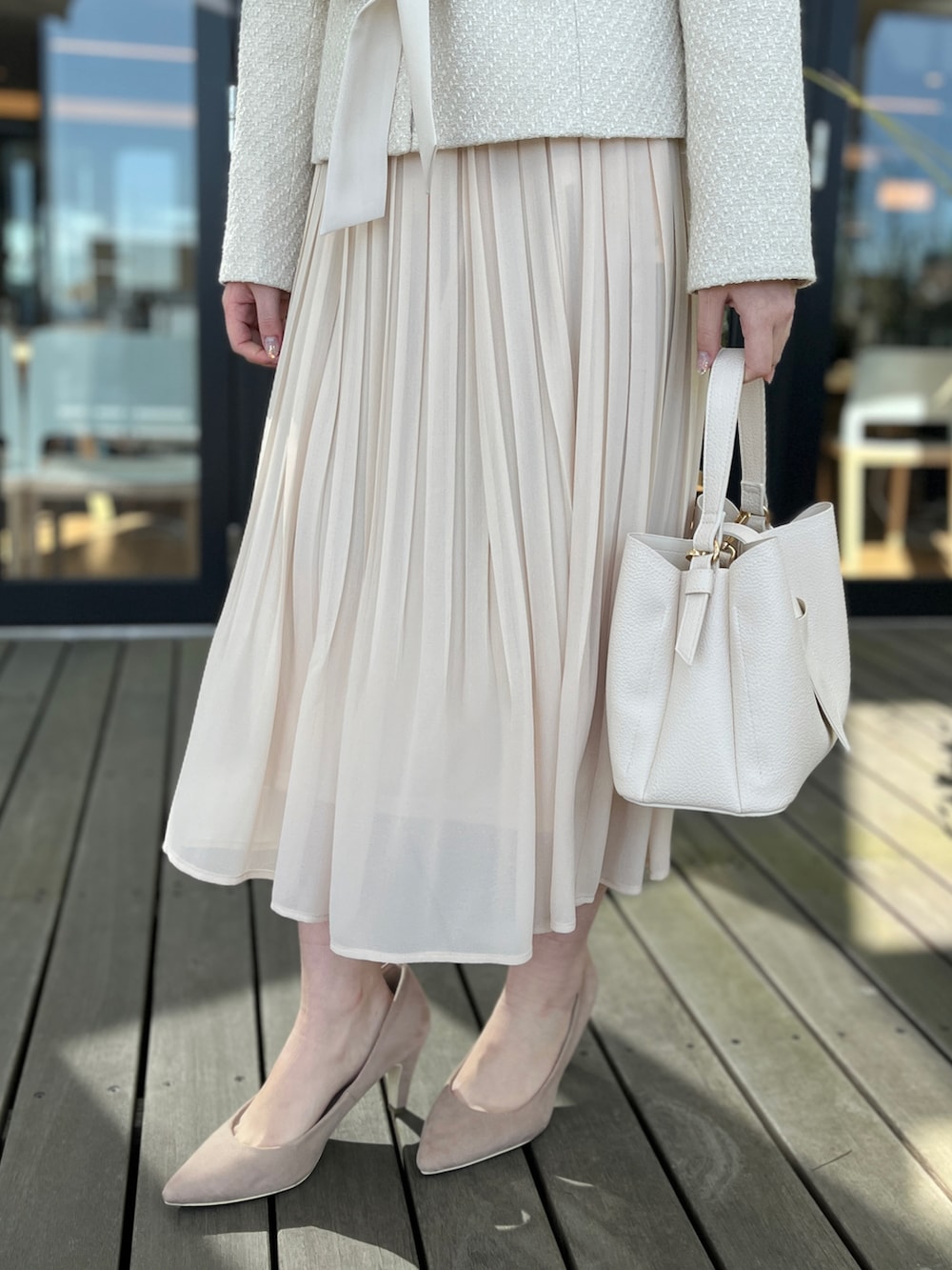ベージュ系のノーカラージャケット、ホワイト系のスカート、ベージュ系のパンプスを着用したレディースの冬コーディネートの5枚目の写真