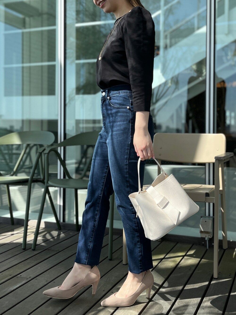 ブルー系のデニムパンツ、ブラック系のTシャツ/カットソー、ベージュ系のパンプスを着用したレディースの春コーディネートの2枚目の写真