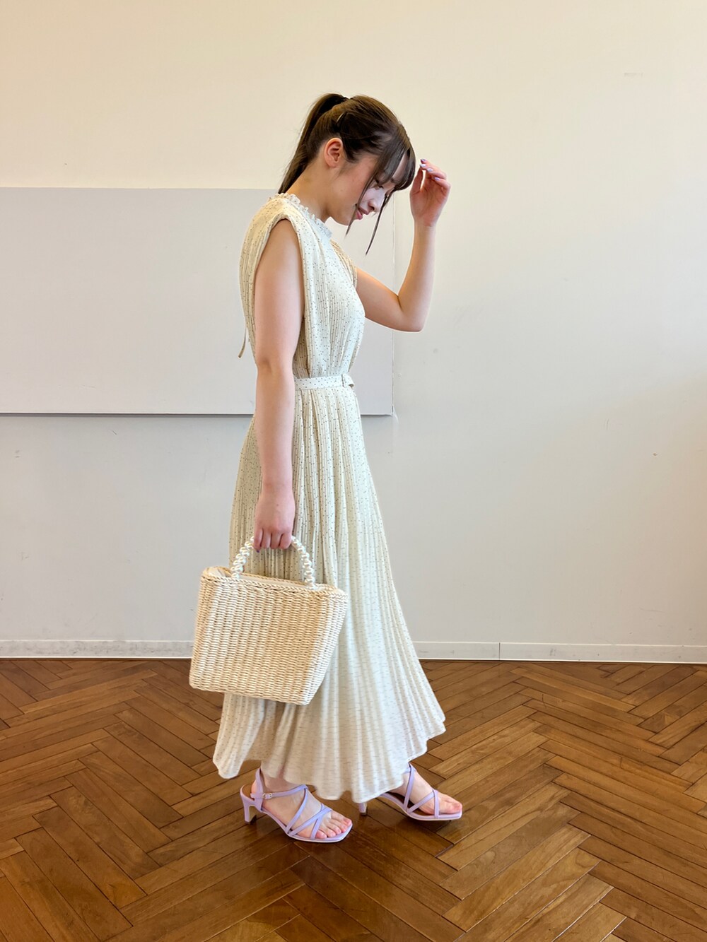 ベージュ系のワンピース、ベージュ系のハンドバッグ、パープル系のサンダルを着用したレディースの春コーディネートの2枚目の写真