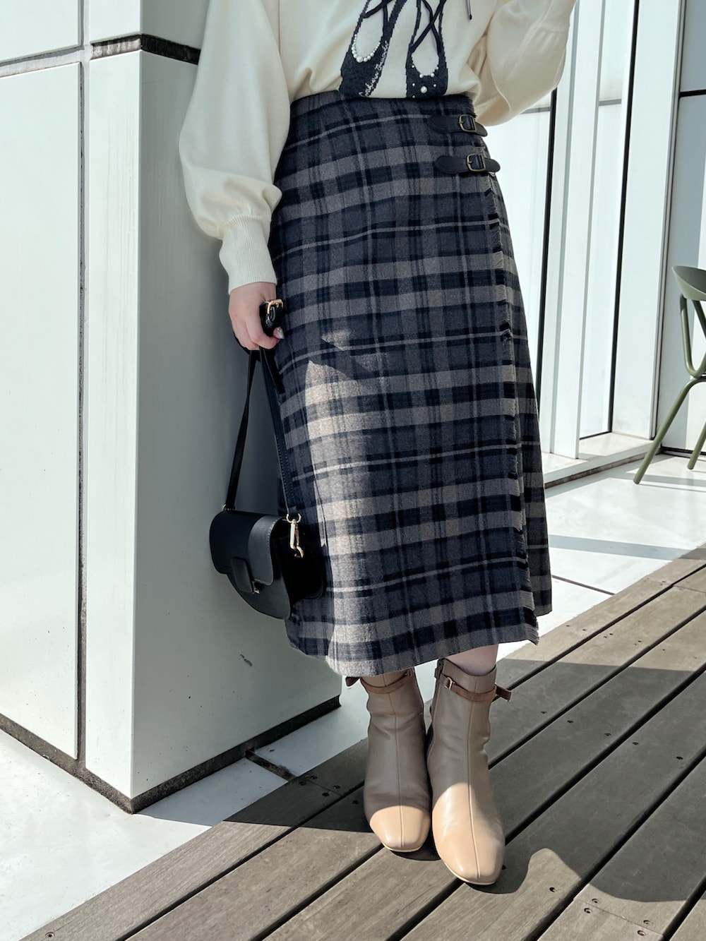 グレー系のスカート、ホワイト系のニット/セーター、ブラック系のショルダーバッグを着用したレディースの秋コーディネートの4枚目の写真