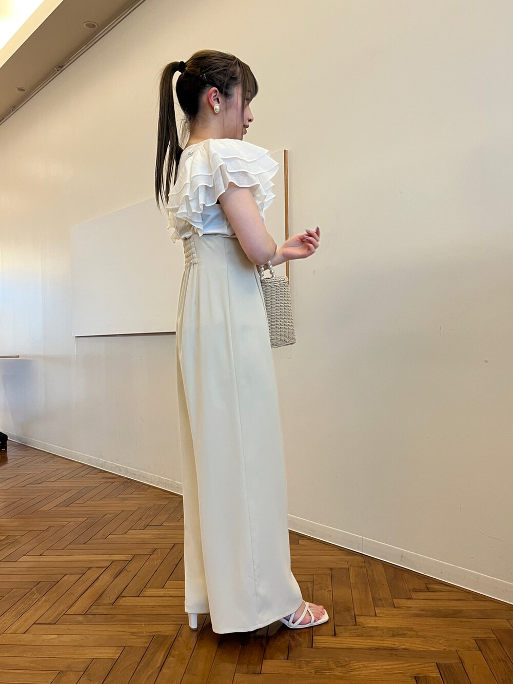 ベージュ系のハンドバッグ、ホワイト系のサンダル、ホワイト系のTシャツ/カットソーを着用したレディースの春コーディネートの2枚目の写真