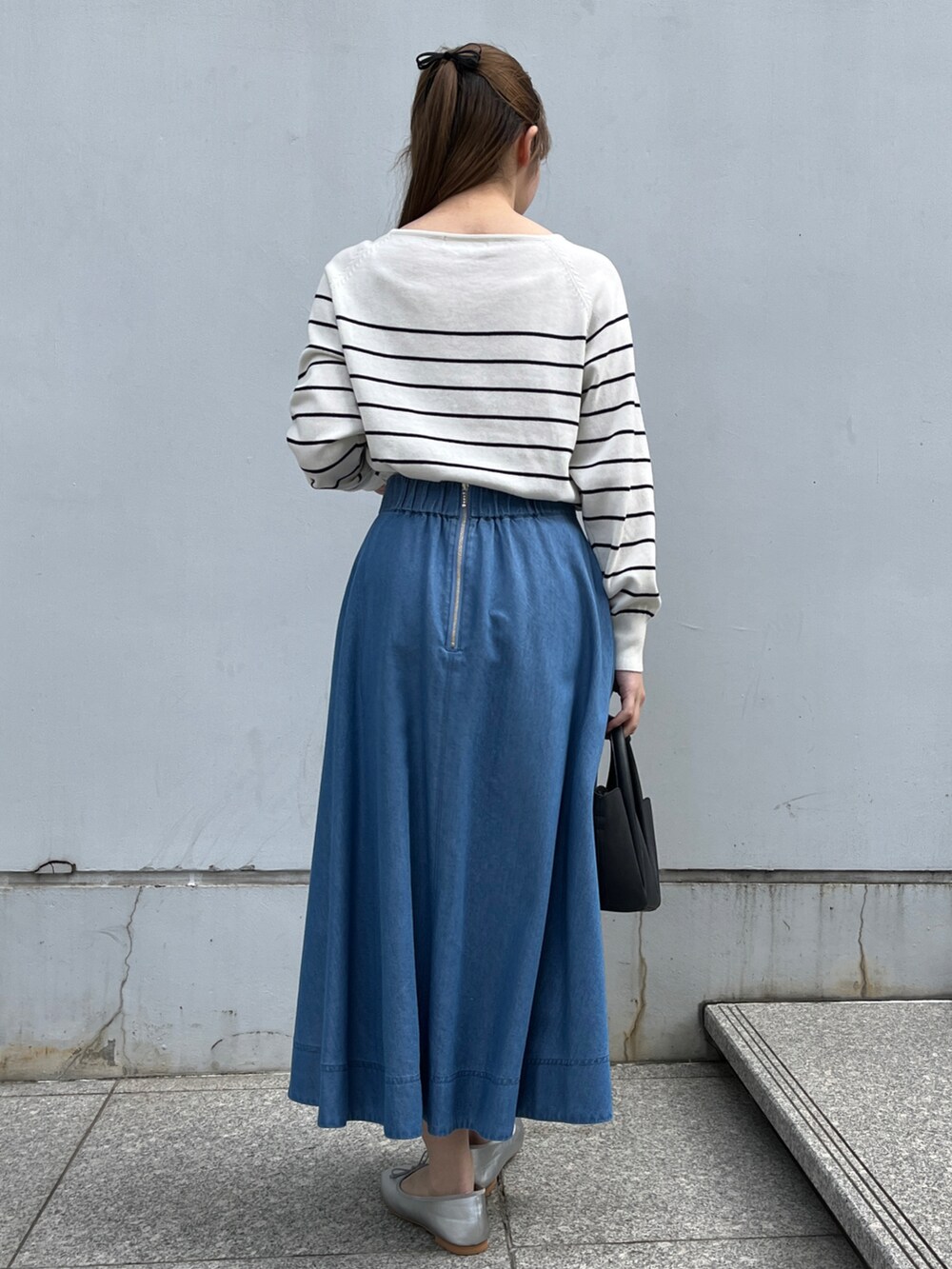 ホワイト系のニット/セーター、ブルー系のスカート、ブラック系のショルダーバッグを着用したレディースの冬コーディネートの3枚目の写真