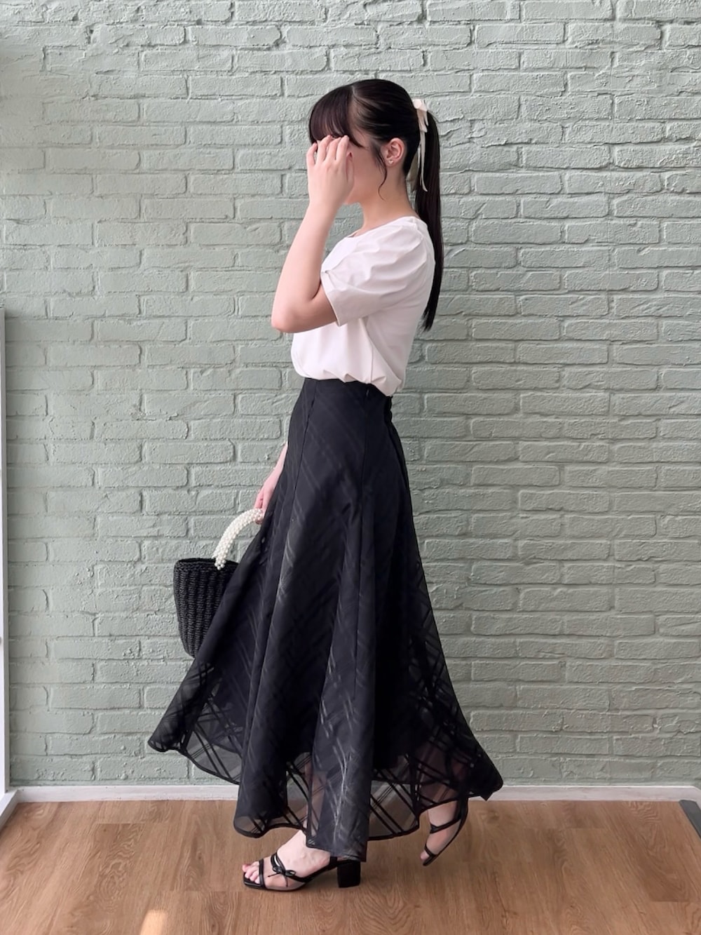 ブラック系のスカート、ホワイト系のTシャツ/カットソーを着用したレディースの夏コーディネートの2枚目の写真