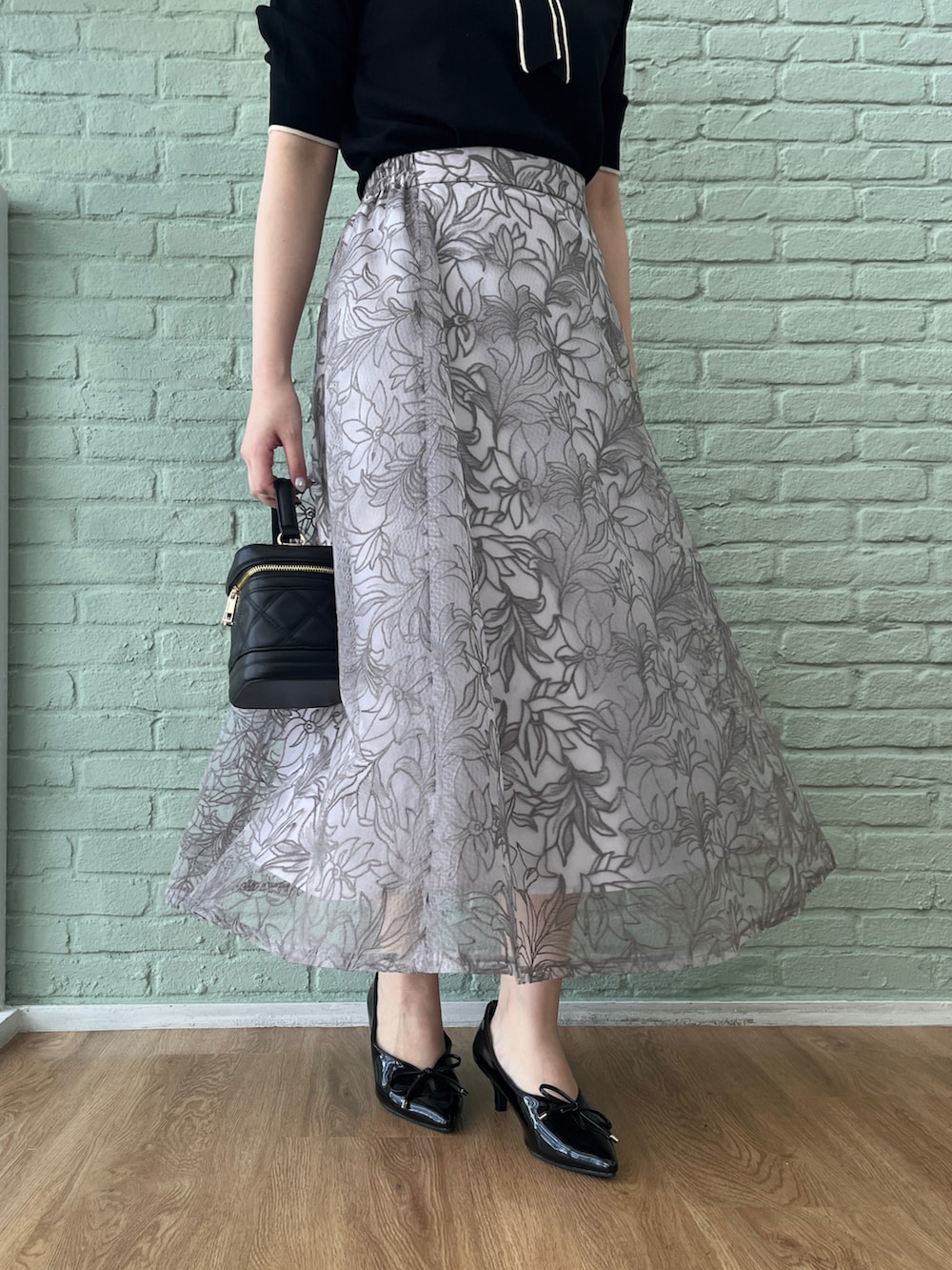 ブラック系のニット/セーター、グレー系のスカート、ブラック系のショルダーバッグを着用したレディースの夏コーディネートの5枚目の写真