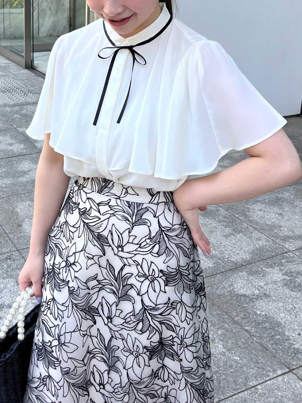 ホワイト系のシャツ/ブラウス、ブラック系のスカート、ブラック系のハンドバッグを着用したレディースの夏コーディネートの4枚目の写真