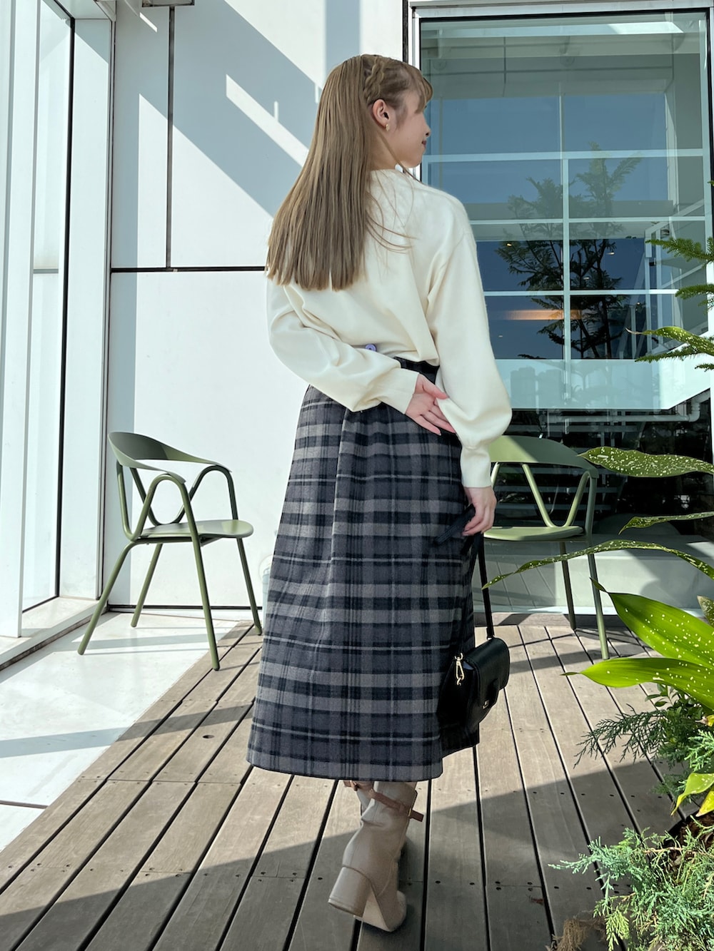 グレー系のスカート、ホワイト系のニット/セーター、ブラック系のショルダーバッグを着用したレディースの秋コーディネートの2枚目の写真