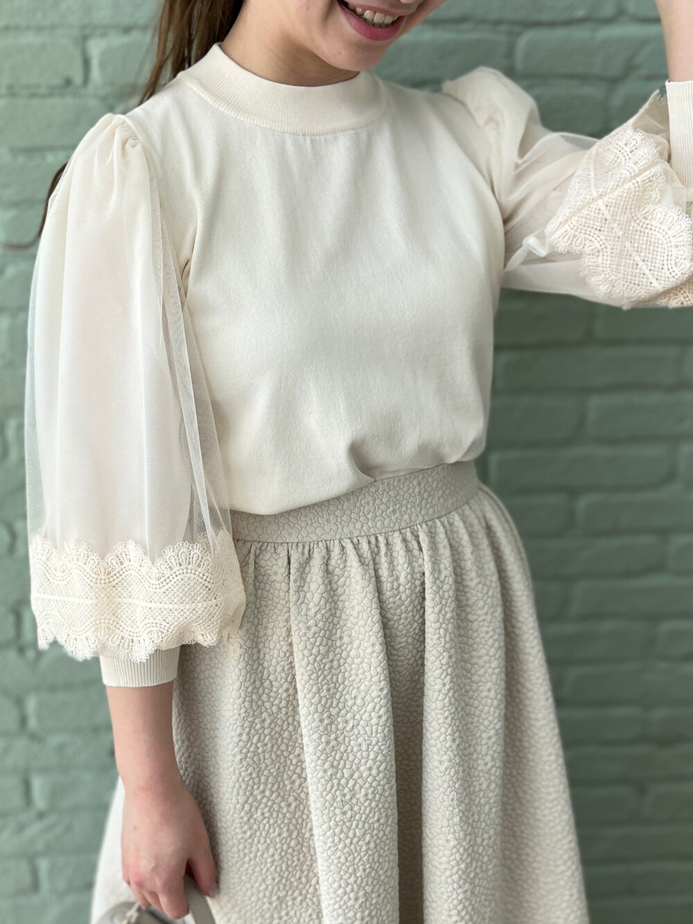 ベージュ系のスカート、ホワイト系のニット/セーター、グレー系のショルダーバッグを着用したレディースの春コーディネートの4枚目の写真