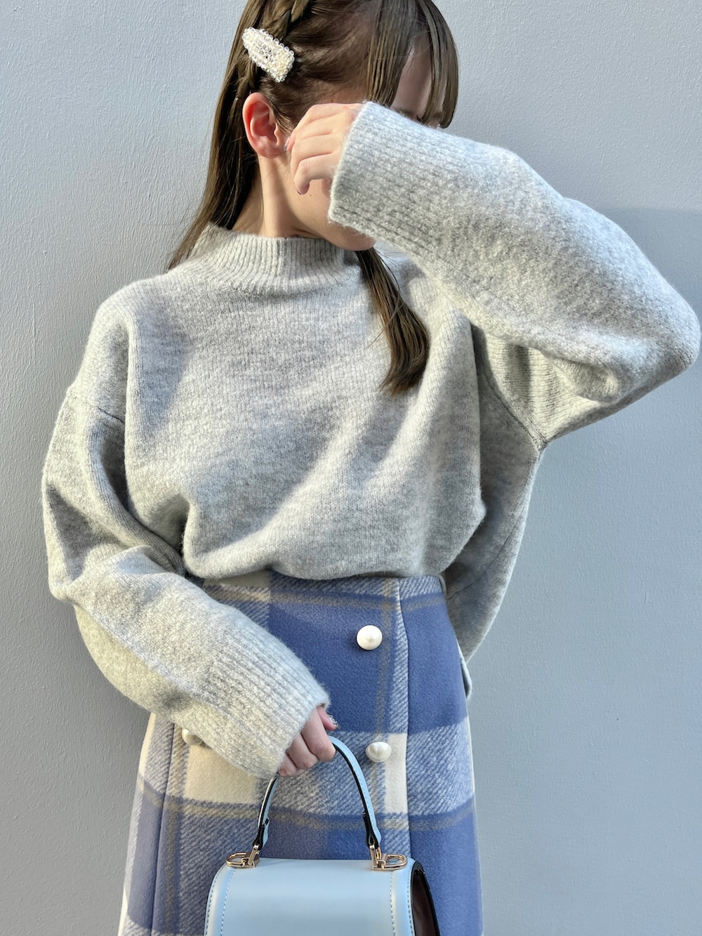 ブルー系のスカート、グレー系のニット/セーター、ベージュ系のブーツを着用したレディースの冬コーディネートの2枚目の写真