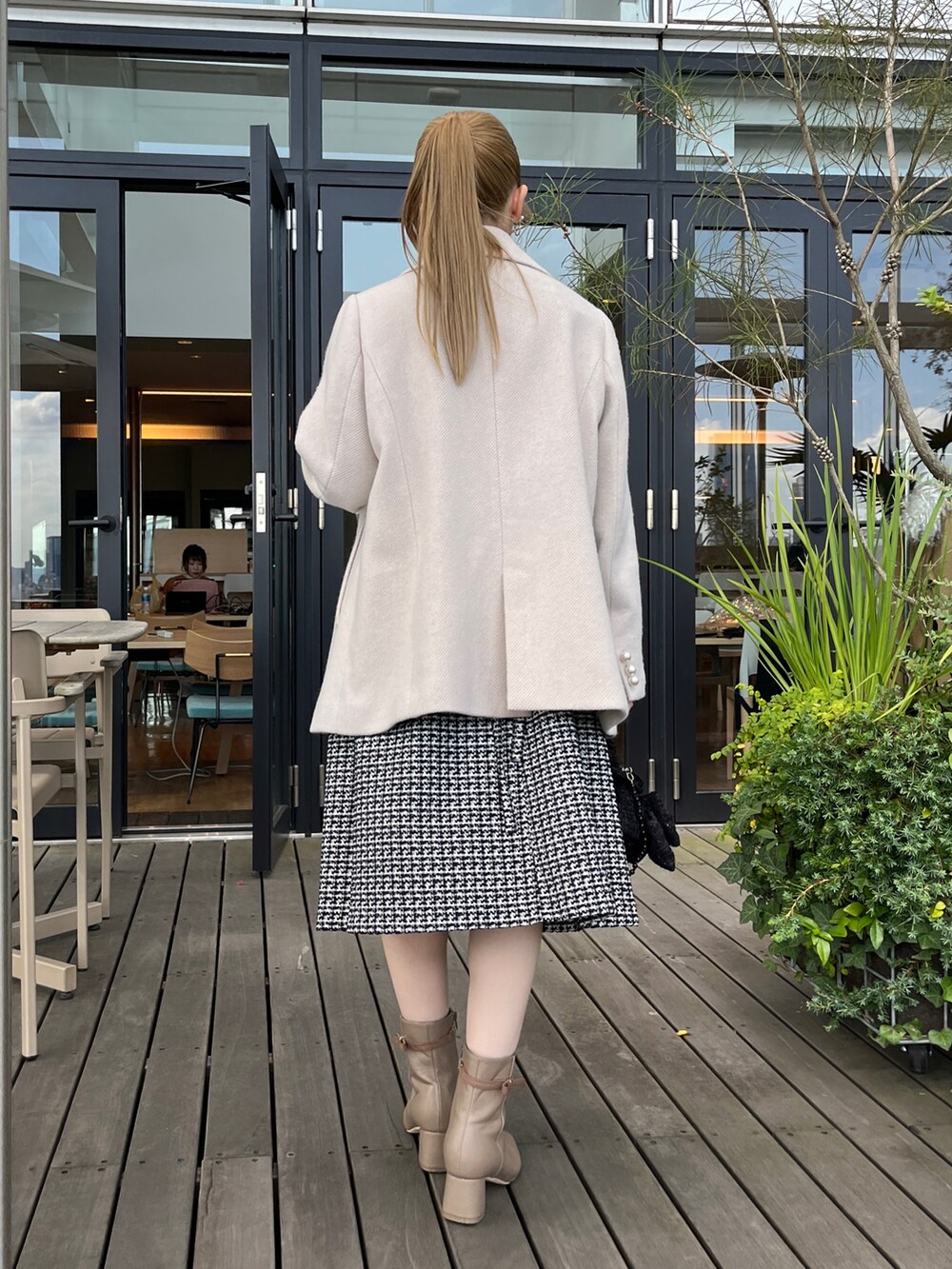 ベージュ系のピーコート、ブラック系のワンピースを着用したレディースの冬コーディネートの3枚目の写真