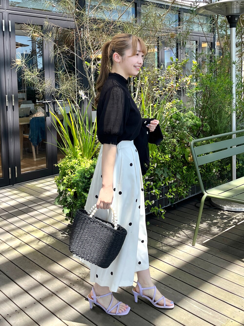 ブラック系のニット/セーター、ブラック系のカーディガン/ボレロ、ベージュ系のスカートを着用したレディースの夏コーディネートの2枚目の写真